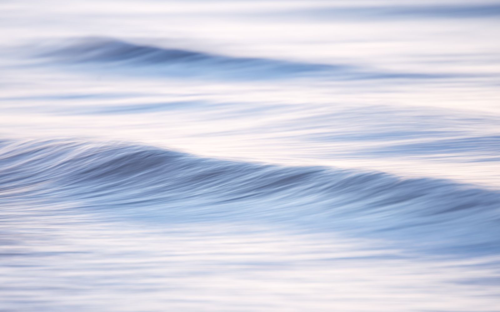 Onde morbide del mare in movimento, in toni azzurri e rosa chiaro